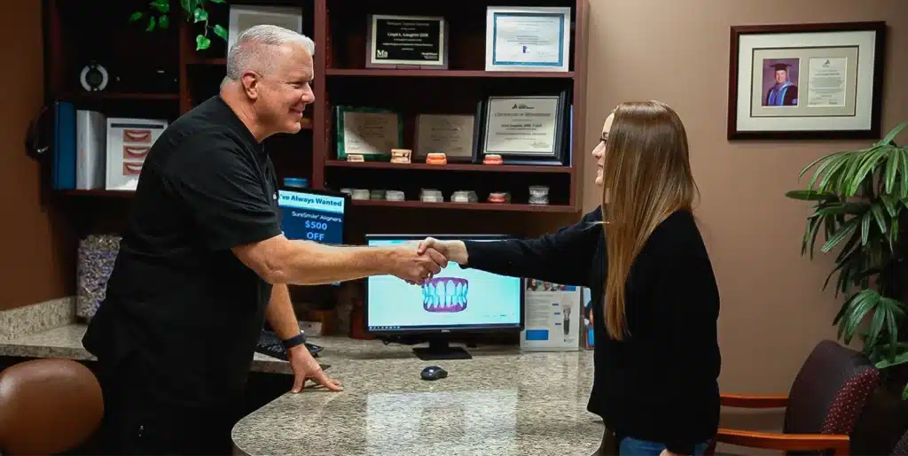 A male dental professional shaking hands with a female patient at Laughlin Dental