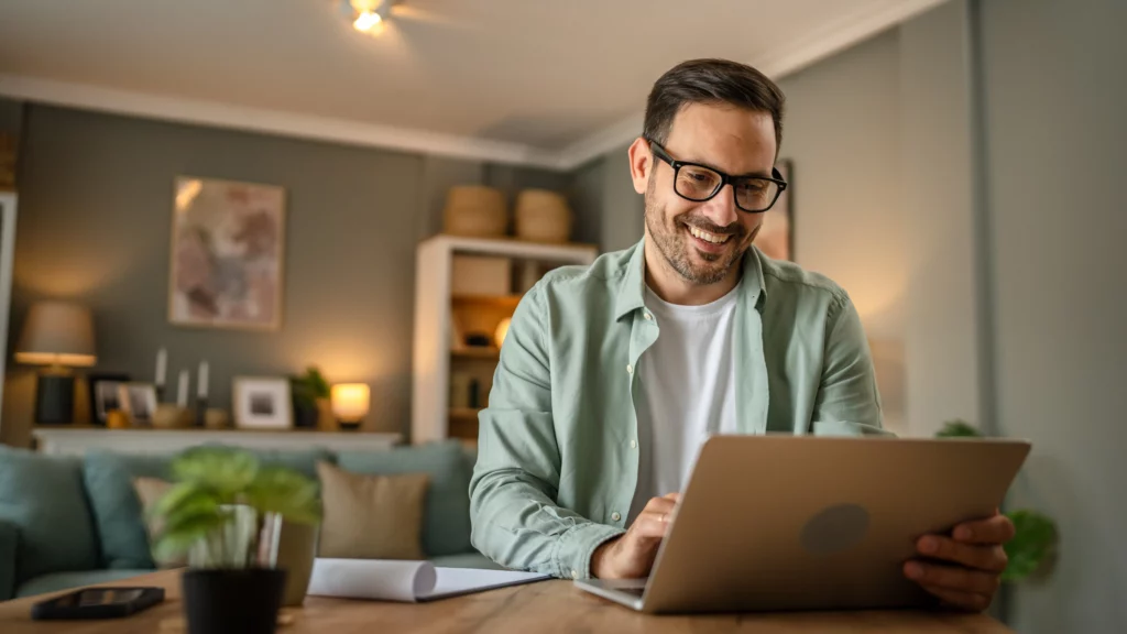 A casually dressed male, possibly a team member, smiles while using a laptop at Laughlin Dental