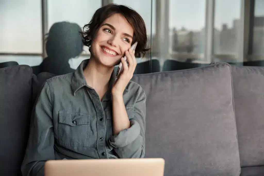 A smiling woman with short hair on a phone call, potentially discussing Financing Options at Laughlin Dental