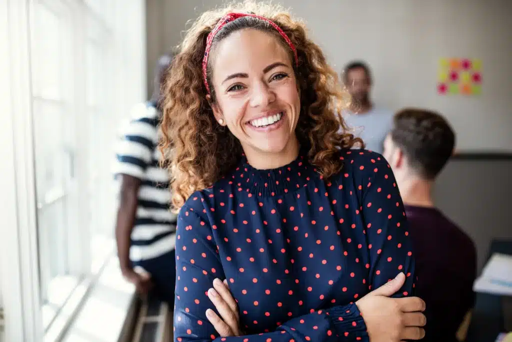 A vibrant woman with curly hair and a red headband, smiling, possibly considering Pocket Reduction Surgery at Laughlin Dental