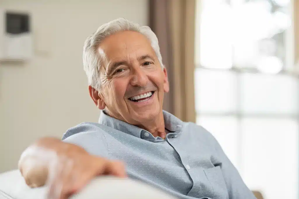 A senior man with a joyful expression and white hair, potentially seeking Gum Disease Treatment at Laughlin Dental
