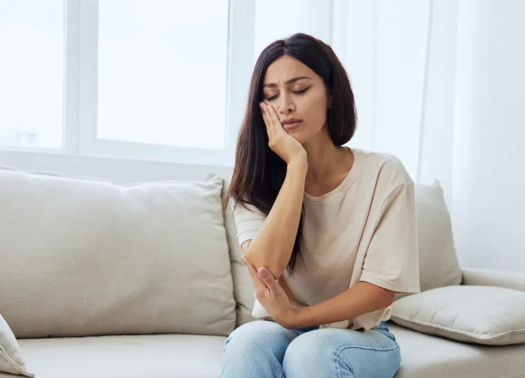 A woman appears to be experiencing tooth pain, potentially indicating a need for Emergency Dentistry at Laughlin Dental
