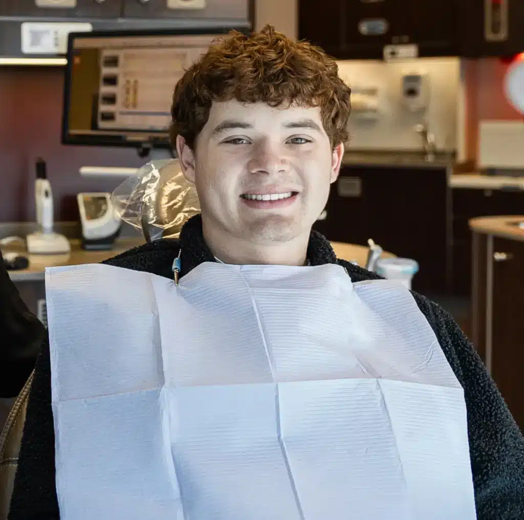 A smiling young man in a dental bib, ready for his appointment at Laughlin Dental
